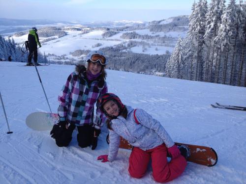 two girls are sitting in the snow with their snowboards at Apartmán u Kamila in Dolní Morava