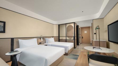 a hotel room with two beds and a flat screen tv at Holiday Inn Hangzhou GCEC in Hangzhou