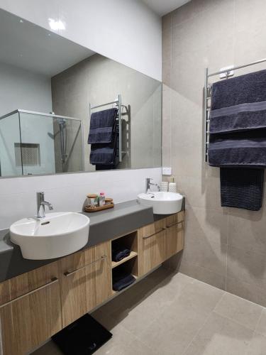 a bathroom with two sinks and a mirror and towels at Holiday at the Beach, Spa Bath, King Bed with TV in Christies Beach