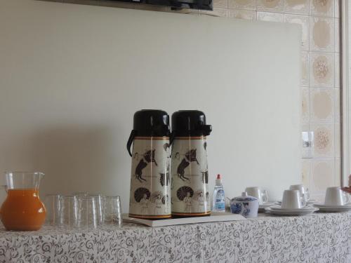 ベント・ゴンサルベスにあるPousada Don Mariniのカウンターの上にグラスと一緒に置かれた2本のコーヒーボトル