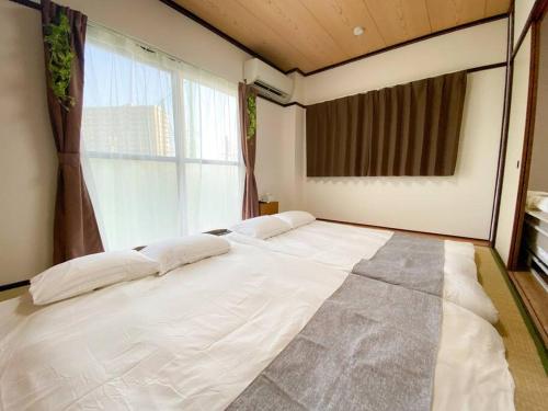 a large white bed in a room with a window at 301 Grand Maison konohana 予約制駐車場,USJや海遊館に最適,駅から徒歩6分 in Osaka