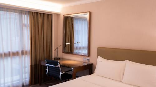 a hotel room with a bed and a desk and a mirror at Holiday Inn Golden Mile by IHG in Hong Kong