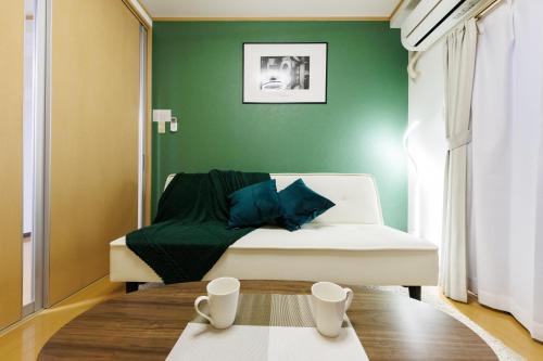 a green room with a bed and a table at アンファング森ノ宮 in Osaka