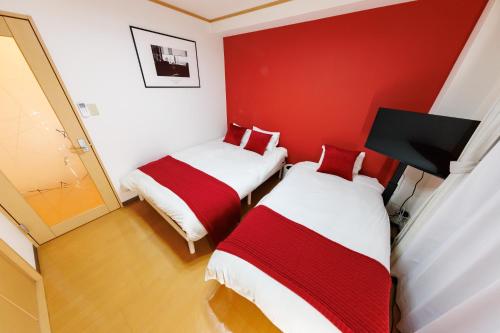 two beds in a room with a red wall at アンファング森ノ宮 in Osaka