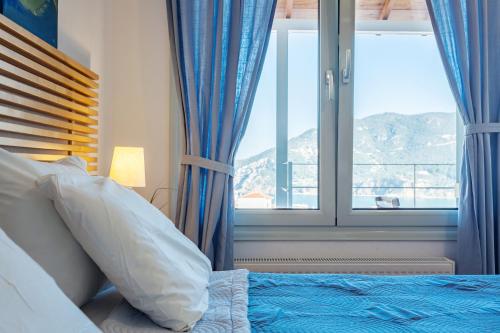 a bedroom with a bed with blue curtains and a window at Thea Home Hotel by Booking Kottas in Skopelos Town