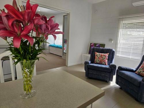 a vase of red flowers on a table in a living room at Blossom Cottage - Cosy Retreat in Penna