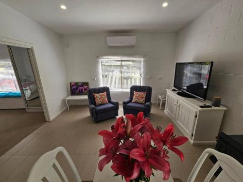 a living room with a vase of red flowers at Blossom Cottage - Cosy Retreat in Penna