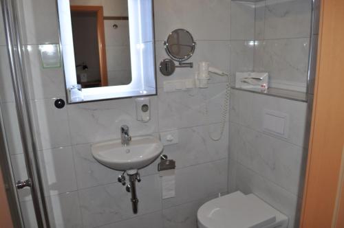 een badkamer met een wastafel, een toilet en een spiegel bij Hotel & Restaurant Bei Hölzchen in Hannover