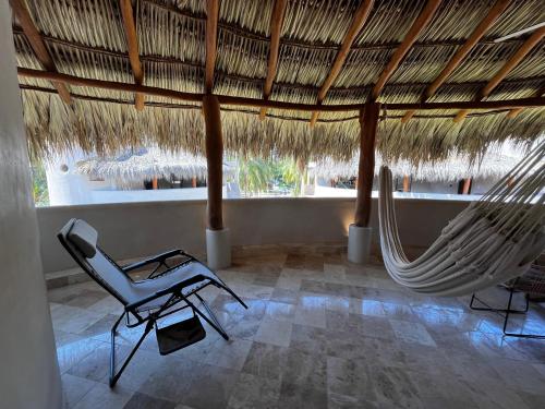 a room with a hammock and a chair in a resort at Villas Cononda in La Majahua