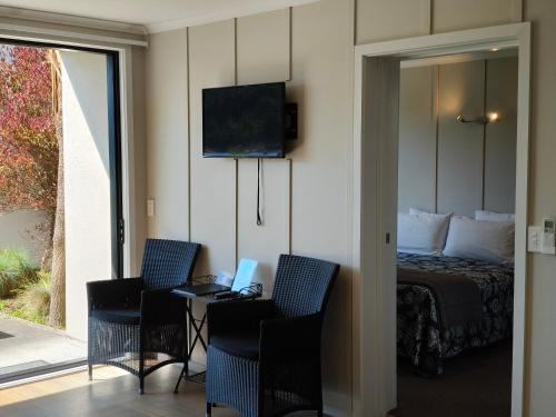 a bedroom with a bed and two chairs and a table with a laptop at Braxmere Lodge in Turangi