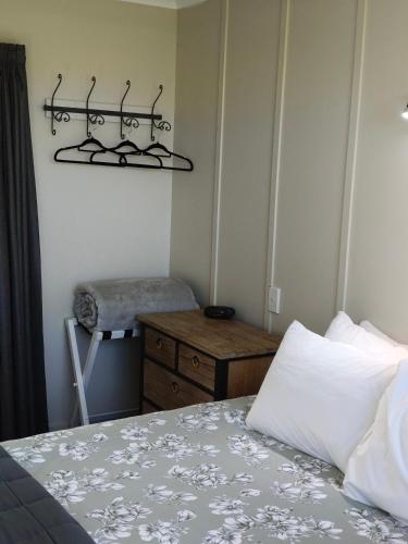 a bedroom with a bed and a dresser and a table at Braxmere Lodge in Turangi