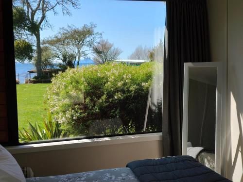 a bedroom with a window looking out at the water at Braxmere Lodge in Turangi