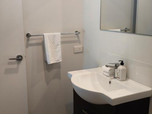 a white bathroom with a sink and a mirror at Braxmere Lodge in Turangi