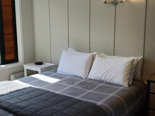 a bedroom with a bed with white pillows and a window at Braxmere Lodge in Turangi