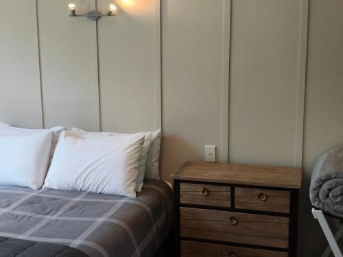 a bedroom with a bed and a wooden dresser at Braxmere Lodge in Turangi