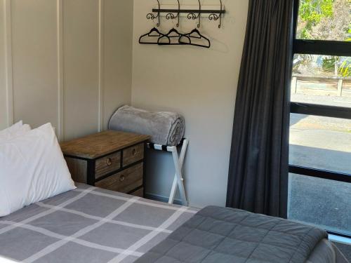 a bedroom with a bed and a chair and a window at Braxmere Lodge in Turangi