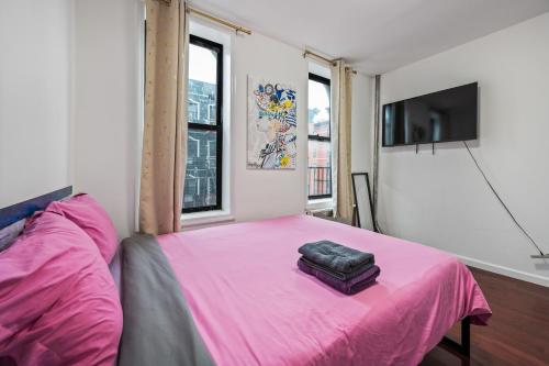 a bedroom with a pink bed and a flat screen tv at Pinky Pinky 2 Bedroom in New York