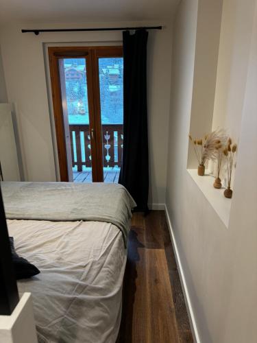 a bedroom with a bed and a door to a balcony at Appartement neuf Méribel hyper centre accès pistes in Méribel