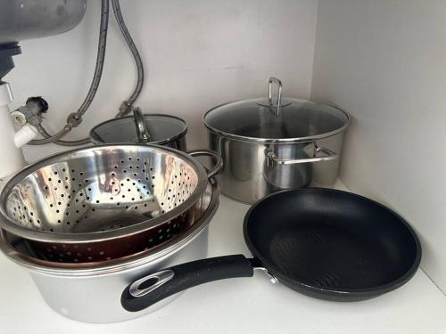 a kitchen counter with three pans and a strainer at Quiet, private studio 1 double bed and extra matress in Mount Pritchard