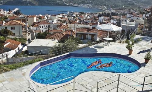 Dos personas están nadando en una piscina en Thea Home Hotel, en Skopelos Town