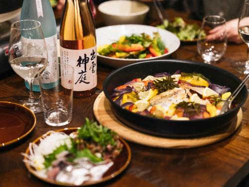 a table with plates of food and a bottle of wine at RITA Izumo Sagiura in Izumo