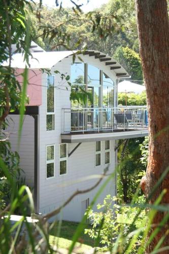 a white building with a balcony on top of it at Starfish Beach House - WIFI - 5 min walk to beach in Hyams Beach