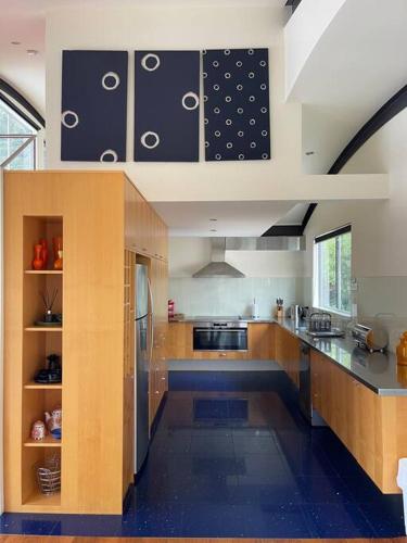 a large kitchen with wooden cabinets and a refrigerator at Starfish Beach House - WIFI - 5 min walk to beach in Hyams Beach