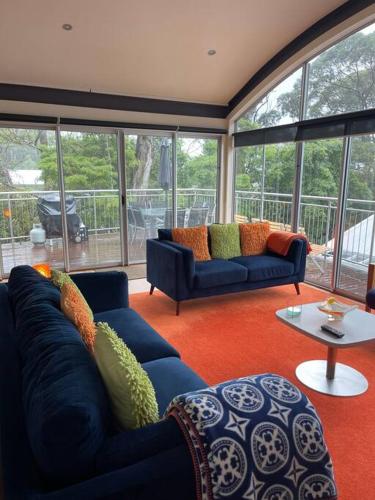 a living room with two blue couches and a table at Starfish Beach House - WIFI - 5 min walk to beach in Hyams Beach