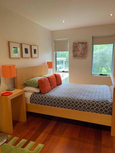a bedroom with a bed with orange pillows and a window at Starfish Beach House - WIFI - 5 min walk to beach in Hyams Beach