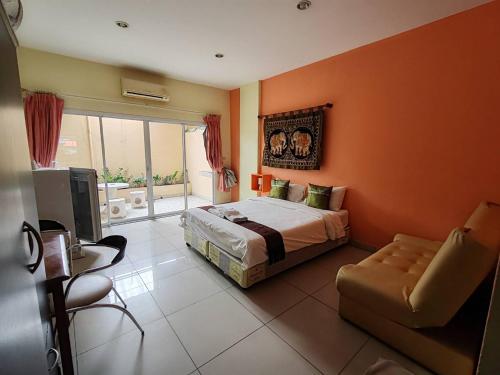a bedroom with orange walls and a bed and a chair at Jomtien Hostel in Jomtien Beach
