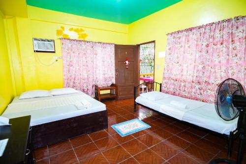 a room with two beds and a fan in it at Gracias Inn Boracay in Boracay