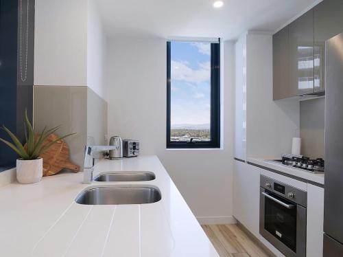 a white kitchen with a sink and a window at Sundale at Southport - Resort-style Panorama in Gold Coast