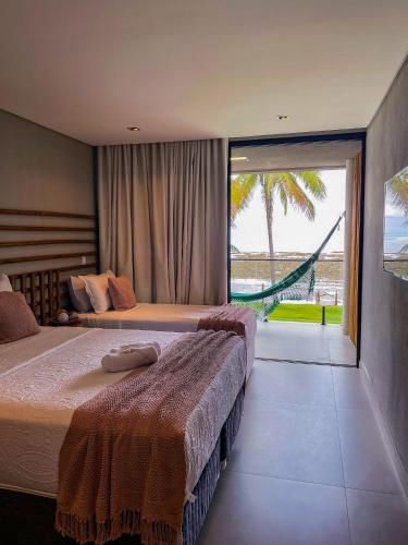two beds in a bedroom with a view of the ocean at Casa Waua | PÉ NA AREIA, rooftop, borda infinita in Barra do Camaragibe