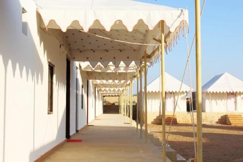 an empty hallway of a white building with a canopy at Golden Heaven Desert Camp in Jaisalmer