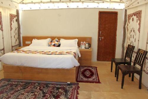 a bedroom with a bed and a table and a chair at Golden Heaven Desert Camp in Jaisalmer