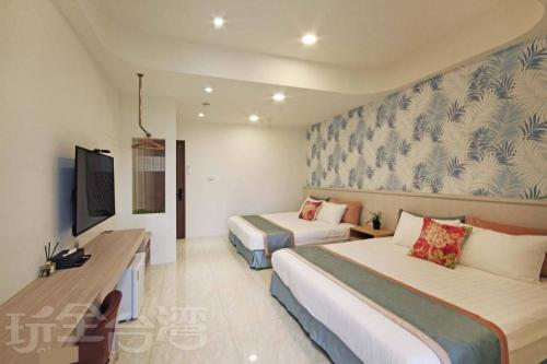 a hotel room with two beds and a tv at Station Sea B&B in Fangliao