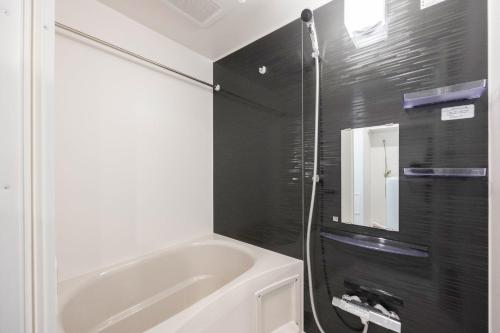 a bathroom with a white tub and a black wall at The Parkcross Ryogoku Midori in Tokyo