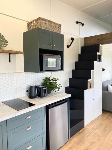 a kitchen with blue cabinets and a staircase at Cosy guest house in Feilding