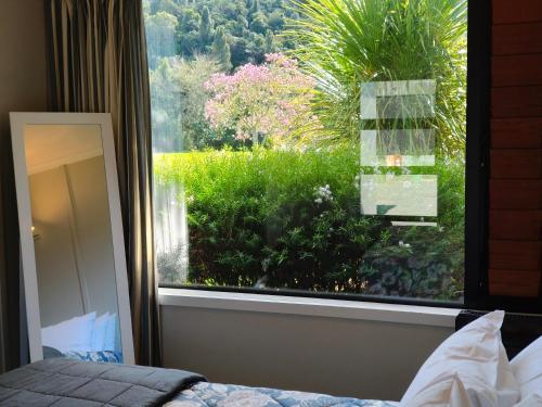 a bedroom with a window looking out at a garden at Braxmere Lodge in Turangi