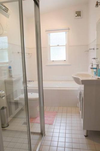 a white bathroom with a shower and a sink at Laguna Blue Beach House-WIFI-Beach Access in Hyams Beach