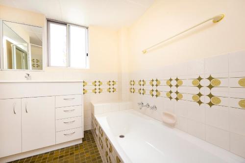 a white bathroom with a tub and a sink at Beachpoint, 401 in Forster