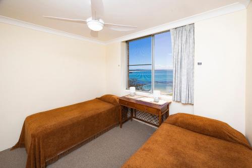 a bedroom with two beds and a table with a window at Beachpoint, 401 in Forster
