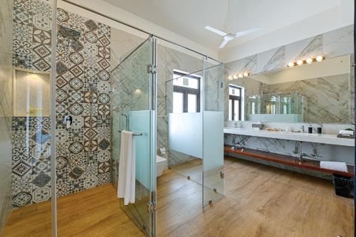 a bathroom with a glass shower and a sink at Melhor Stays Villa - L-M102 Luxurious 4BHK villa with private pool, Anjuna in Anjuna