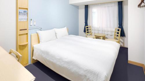 a bedroom with a large white bed and a table at Toyoko Inn Kagoshima chuo eki Higashi guchi in Kagoshima