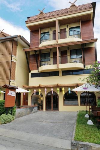 a large building with tables and umbrellas in front of it at Old Town Chiangmai Boutique in Chiang Mai