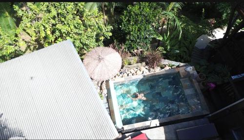 a swimming pool with a umbrella next to at OHANA Jungle Lodges in Les Avirons