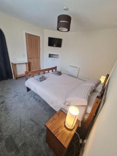 a bedroom with a bed and a table with a lamp at Modern 3 Bedroom Property centrally based in Balivanich