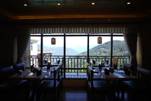 a dining room with tables and chairs and a large window at Mount Magnolia Boutique Hotel & Spa in Pelling