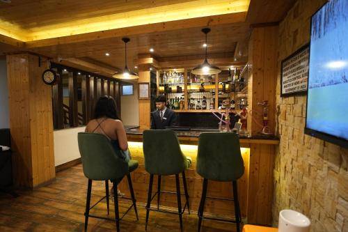 a woman sitting at a bar in a restaurant at Mount Magnolia Boutique Hotel & Spa in Pelling