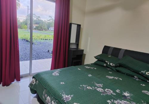 a bedroom with a bed with a green comforter and a window at One Lot - Villa L in Arau